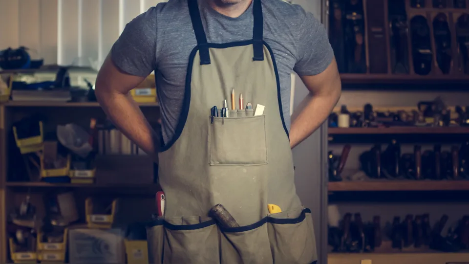 Maker in a work apron standing in his workshop